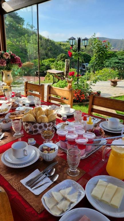 Mesa do café com pães de queijo, frutas, iogurtes e suco