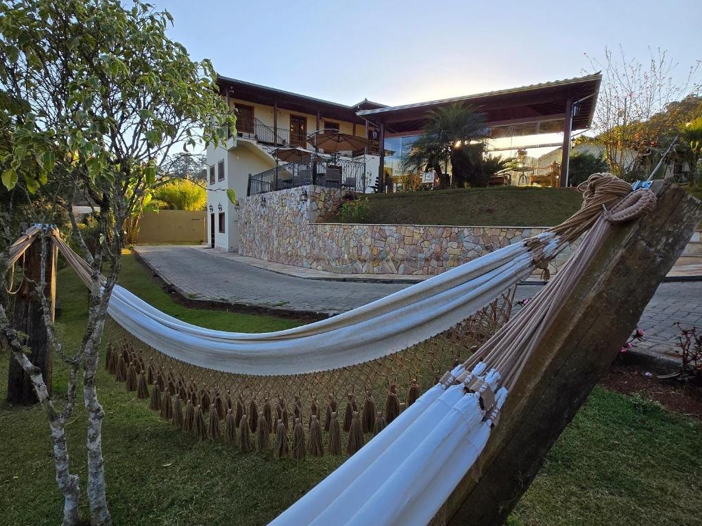 Rede armada no jardim ao entardecer, com a pousada ao fundo